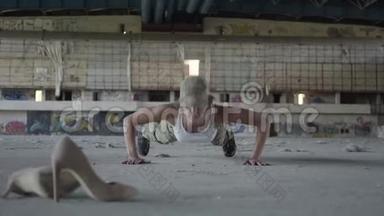 一位身穿军装的强壮年轻女子从一座废弃建筑的混凝土地板上<strong>扭动</strong>身体